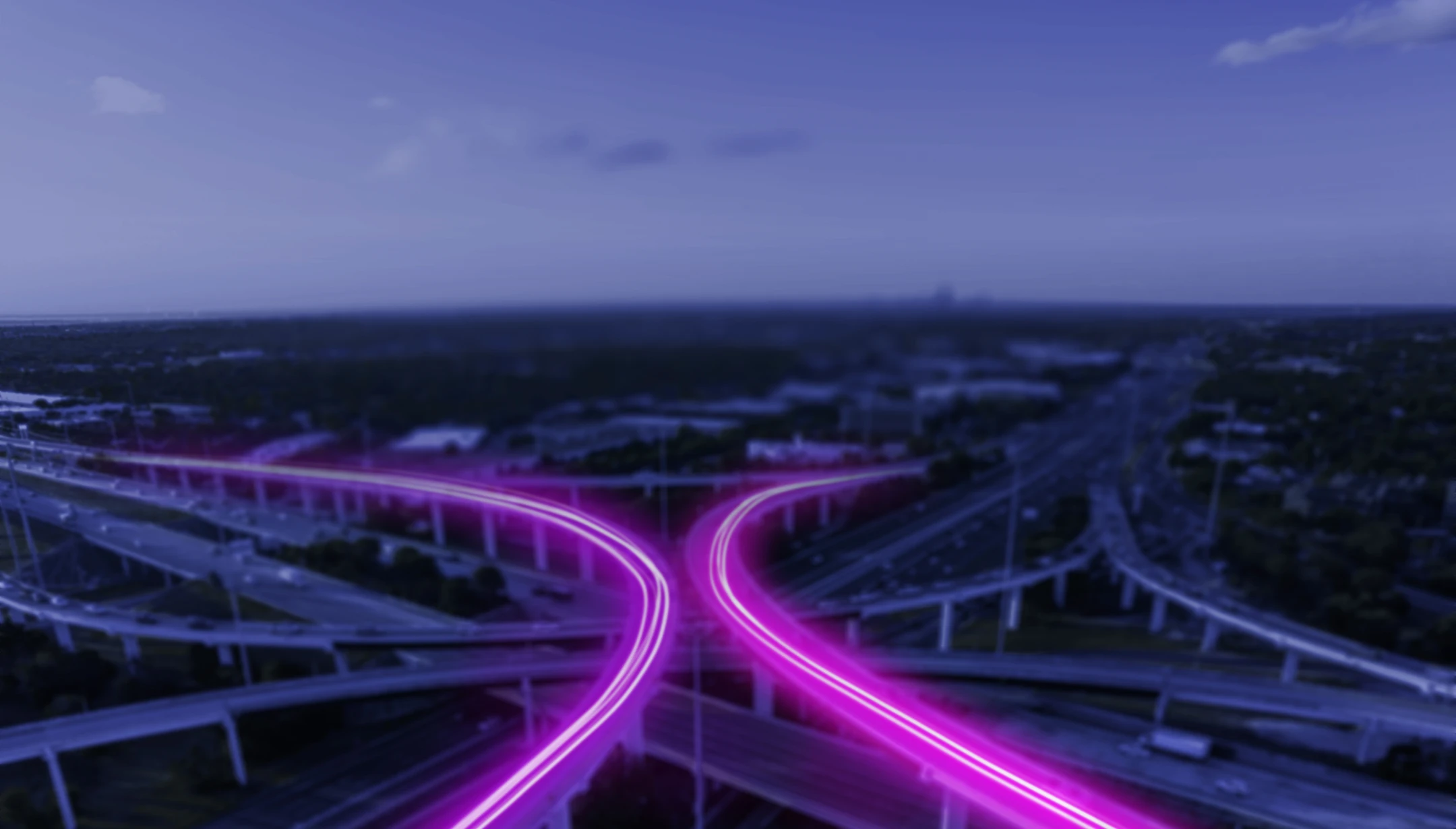 A busy highway system with purple light tracing over the cars