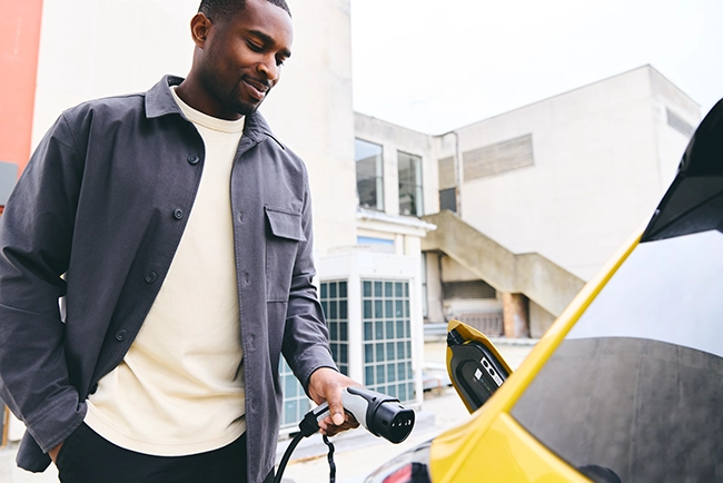 Man plugging in his electric car outside an office