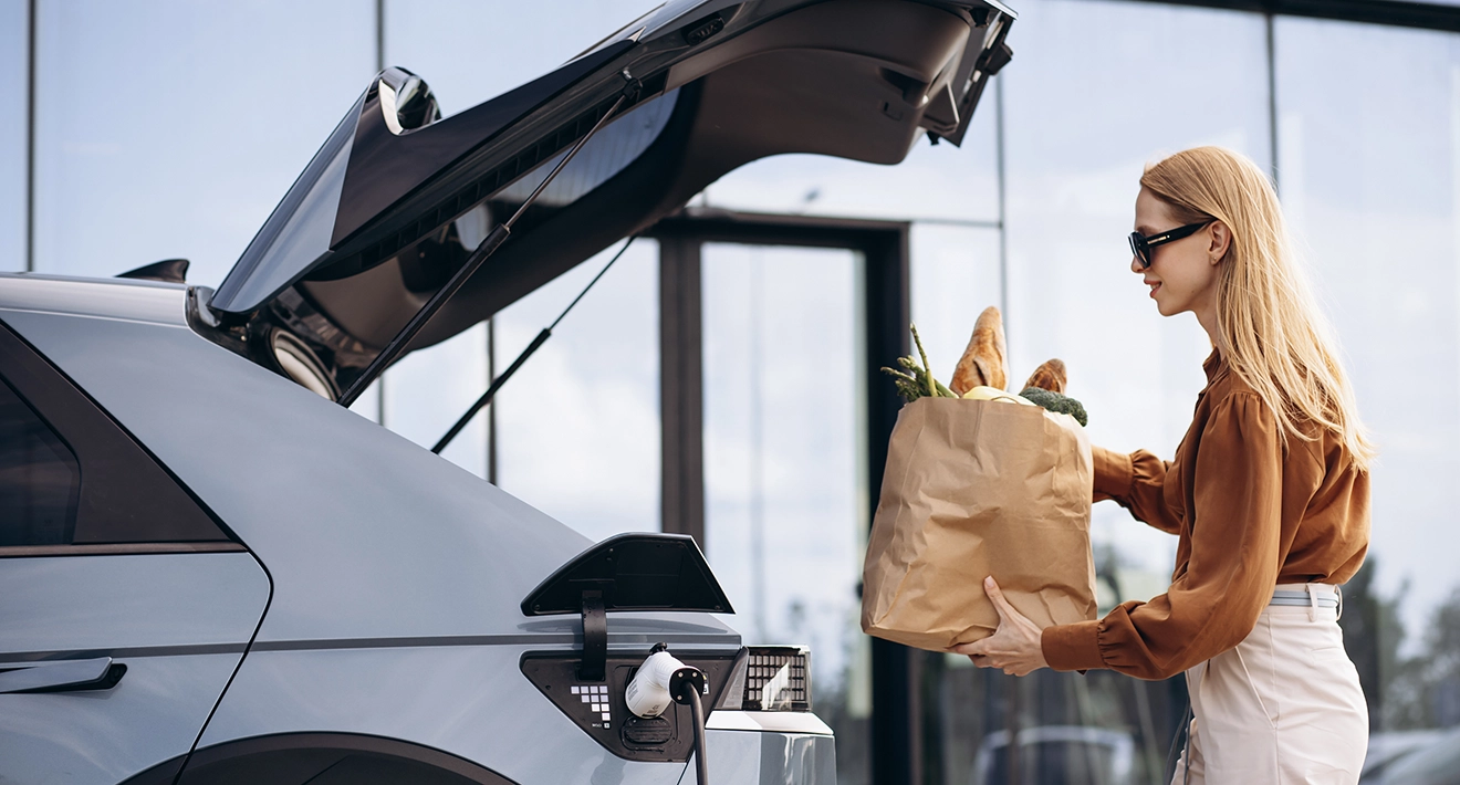 A woman loading groceries into her electric car