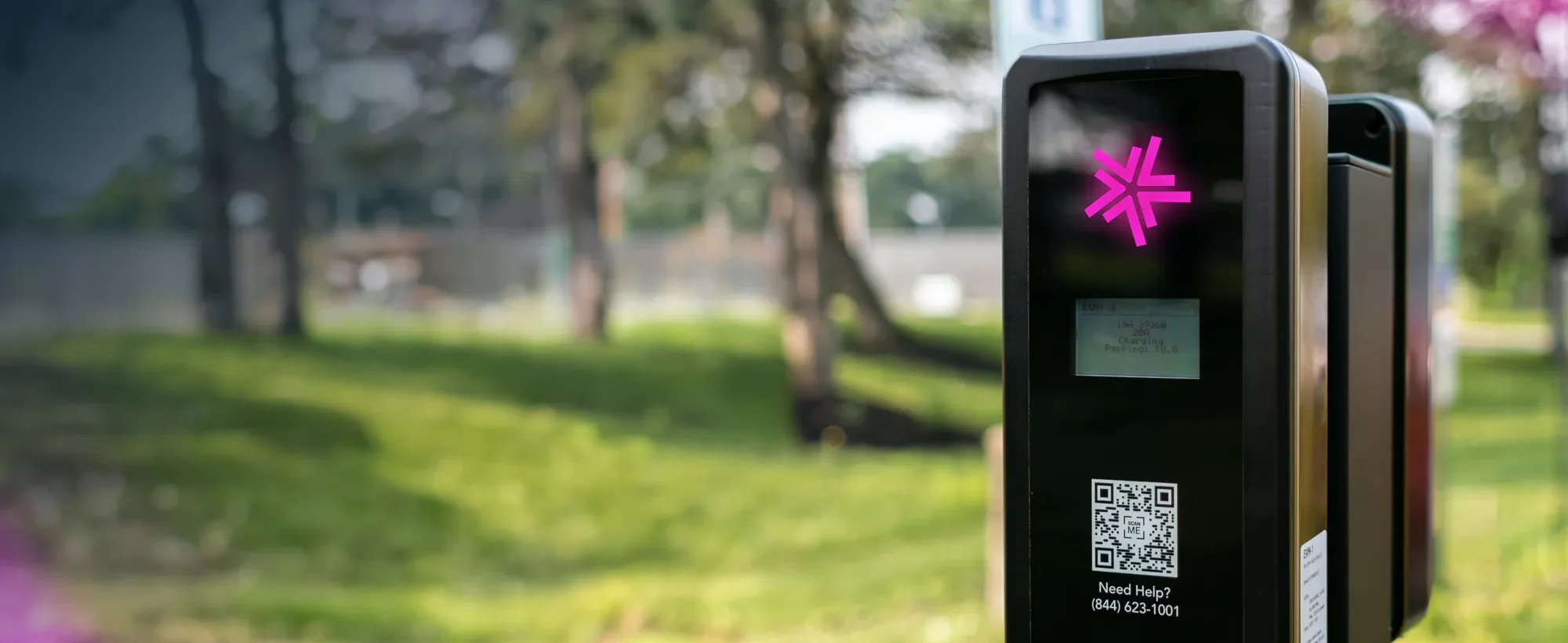 A Lynkwell EV charging station at a park with lots of trees in the background