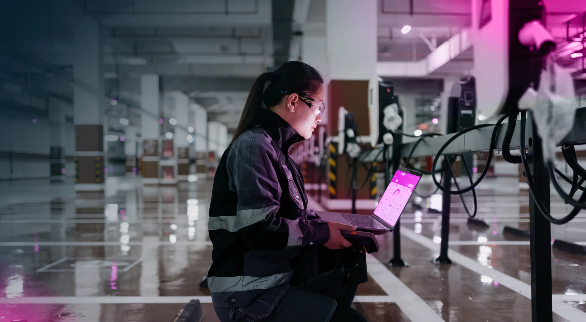 A factory worker reviewing EV charging data on a laptop using Lynkwell's EV charging software