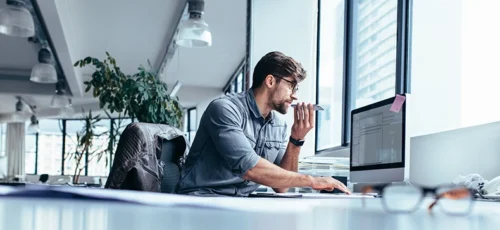 A male executive working on computer and talking on mobile phone